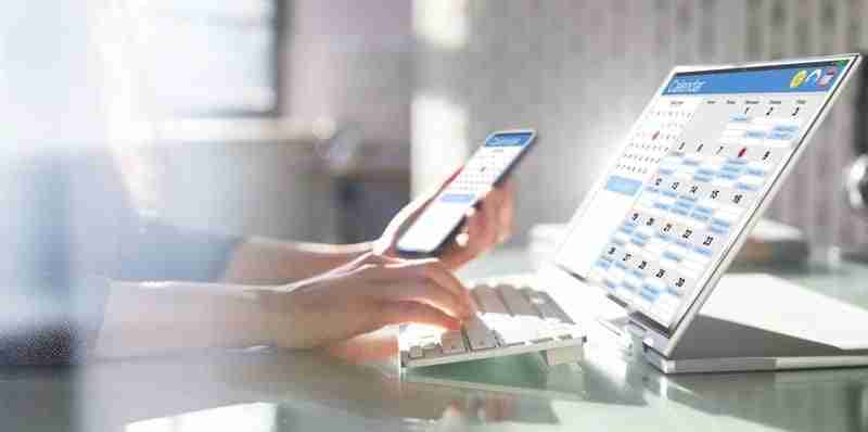 person updating their calendar on their phone and laptop